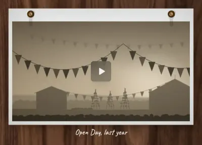 A video clip of bunting strung between two huts over the plots, paused, a play button resting over the frame, captioned Open Day, last year.